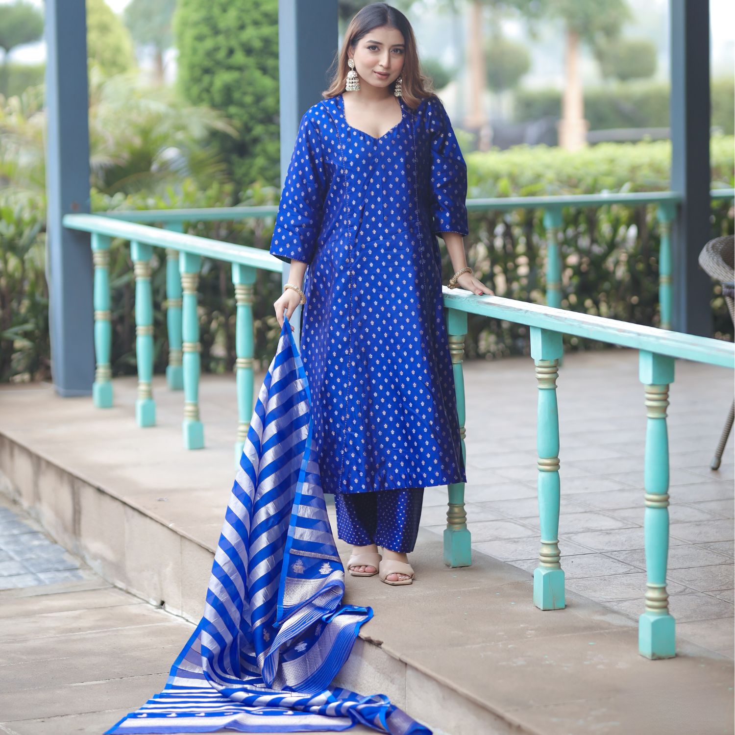 Full view of a woman wearing a royal blue handwoven Banarasi silk suit with gold sona rupa boota and an organza dupatta.