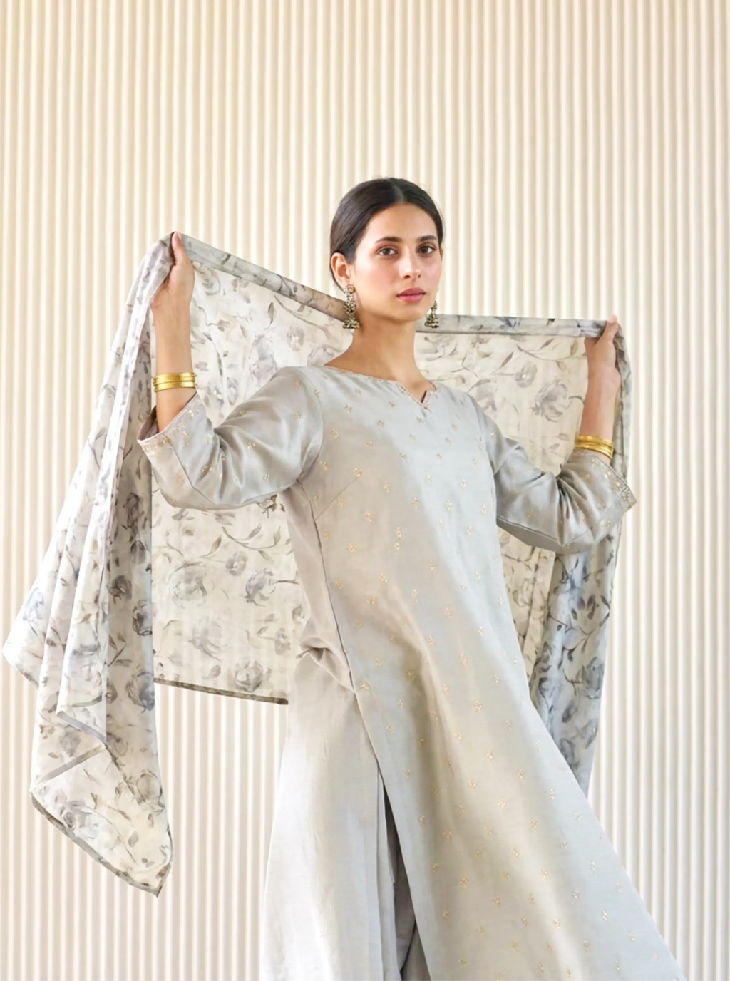 Model in an elegant grey Chanderi cotton silk ethnic suit holding up a beautiful floral print matching dupatta by Arzo India.
