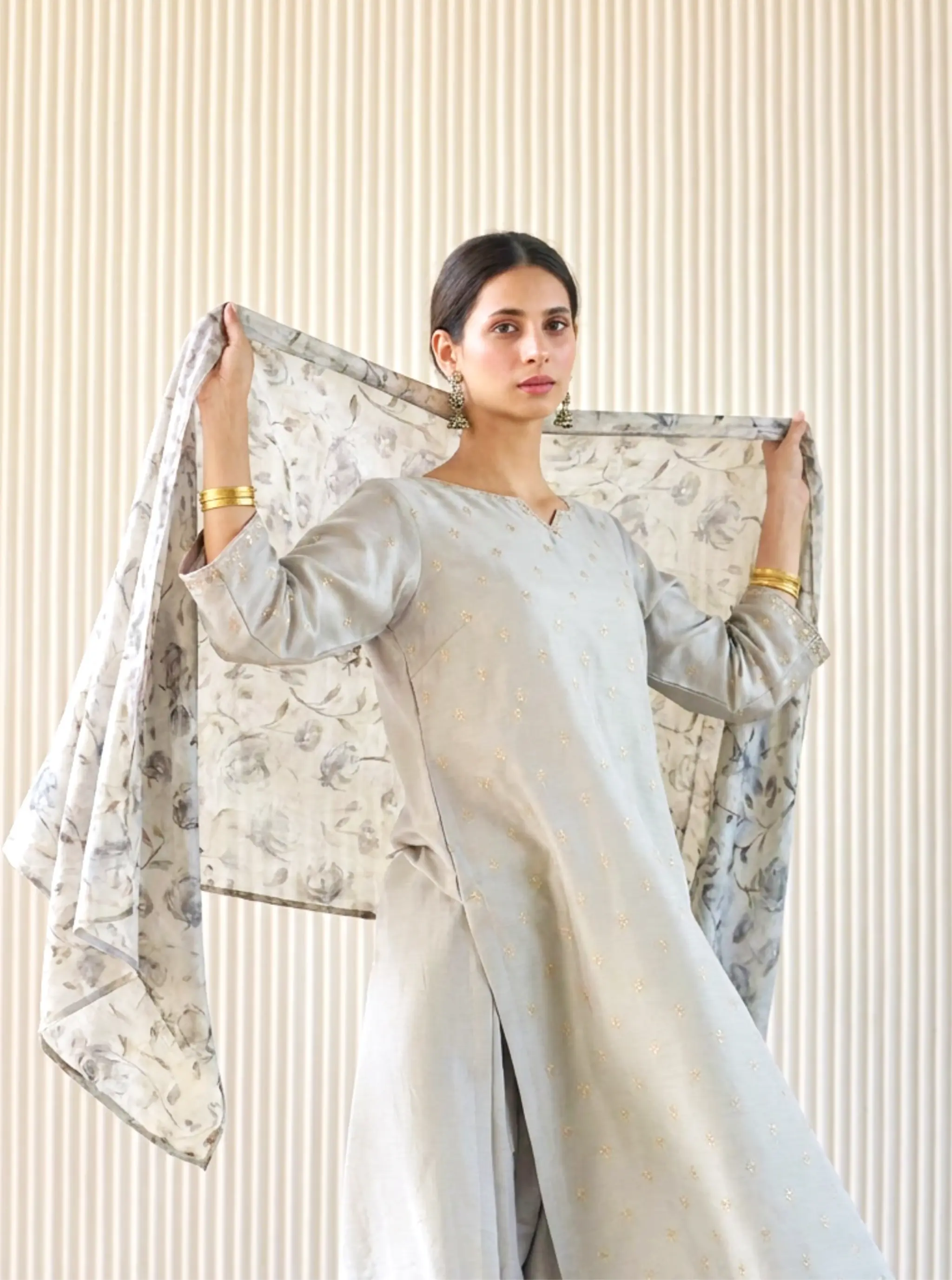 Model in an elegant grey Chanderi cotton silk ethnic suit holding up a beautiful floral print matching dupatta by Arzo India.
