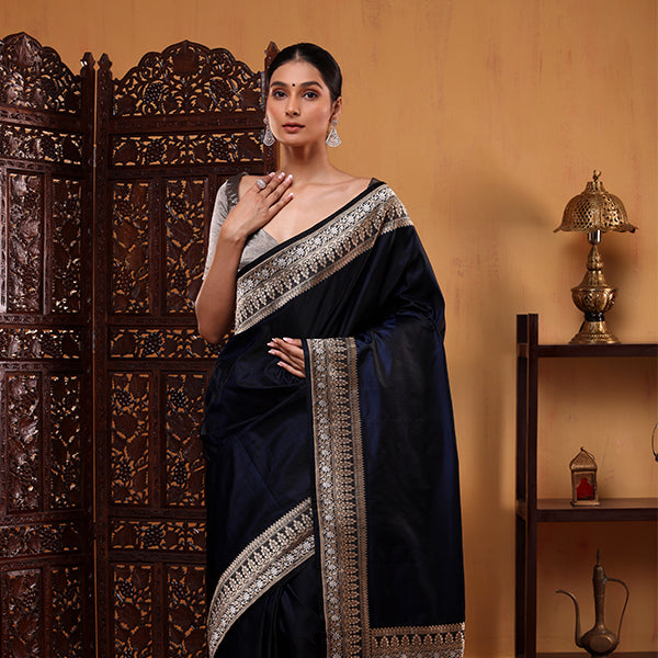 A model posing in a royal blue handwoven Mashru silk saree featuring a detailed silver zari border and an elegant draped palla.