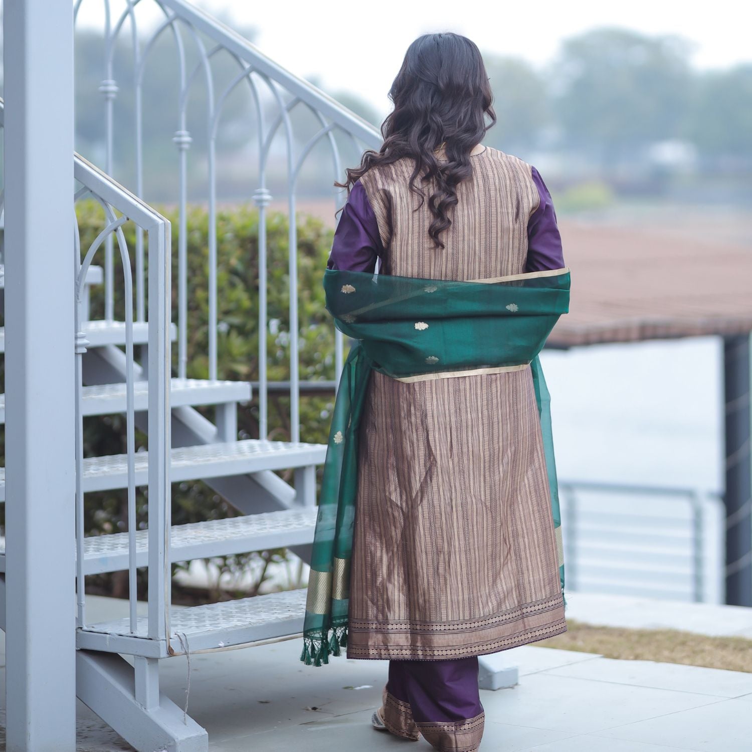 Back view of a grape purple Banarasi silk suit with vertical gold boota weaving and a green kora dupatta draped over the shoulders.