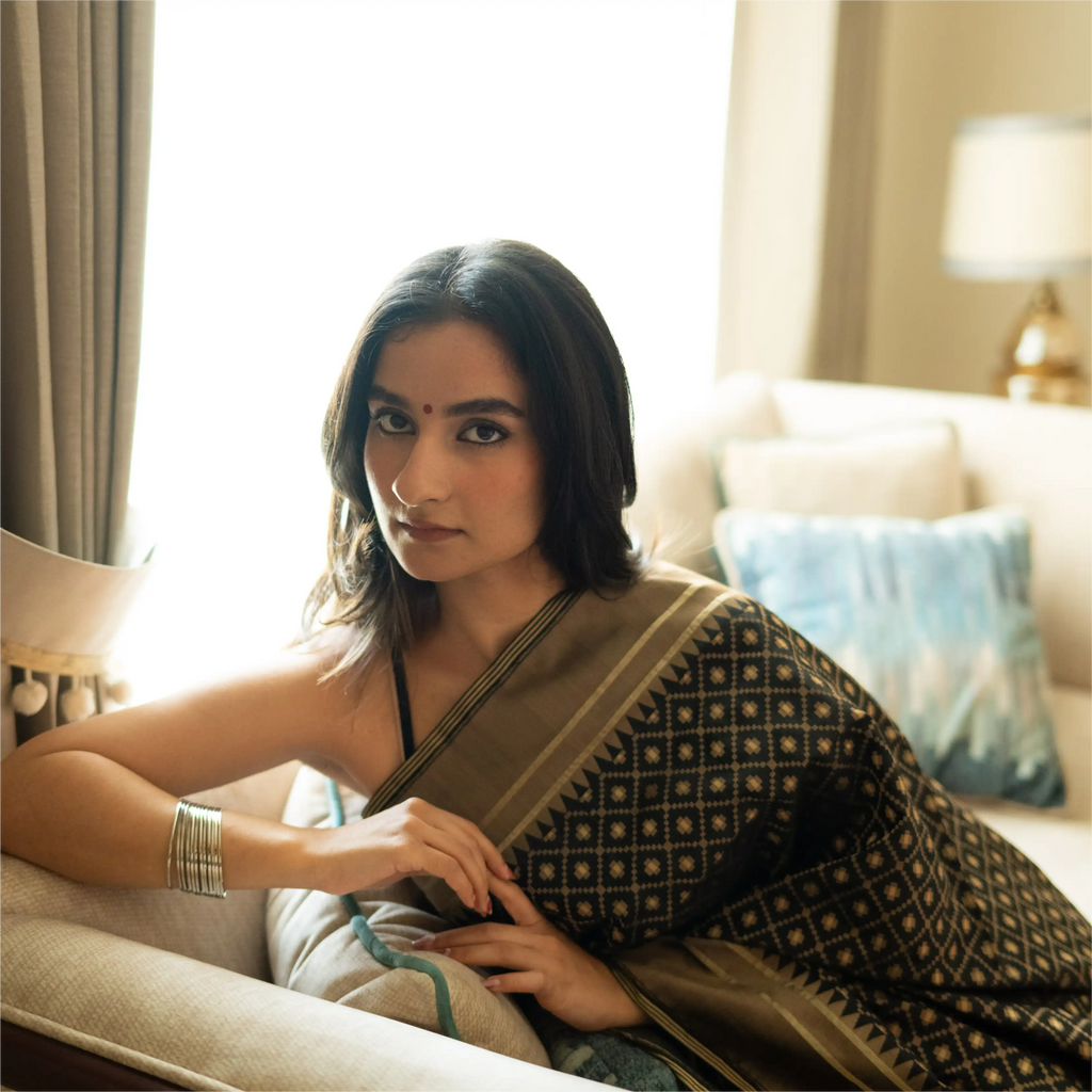 Portrait of a model wearing a Black Handwoven Katan Silk Saree, showcasing the intricate diamond-patterned zari work and high-quality silk texture.
