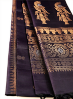 Close-up shot of a deep black Patola silk saree showing delicate gold zari bootis on the pleats, paired with an intricately woven zari pallu featuring gold bird and floral motifs on a dark backdrop.