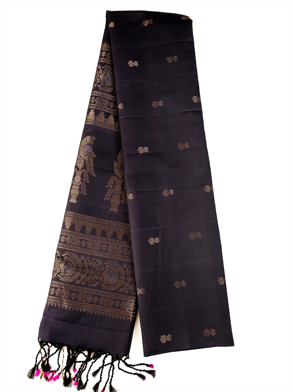 Deep black pure Patola silk saree folded length-wise against a white background, highlighting delicate gold zari floral bootis across the body, an intricately woven zari pallu along the border, and decorative black and pink tassel fringe at the bottom edge.