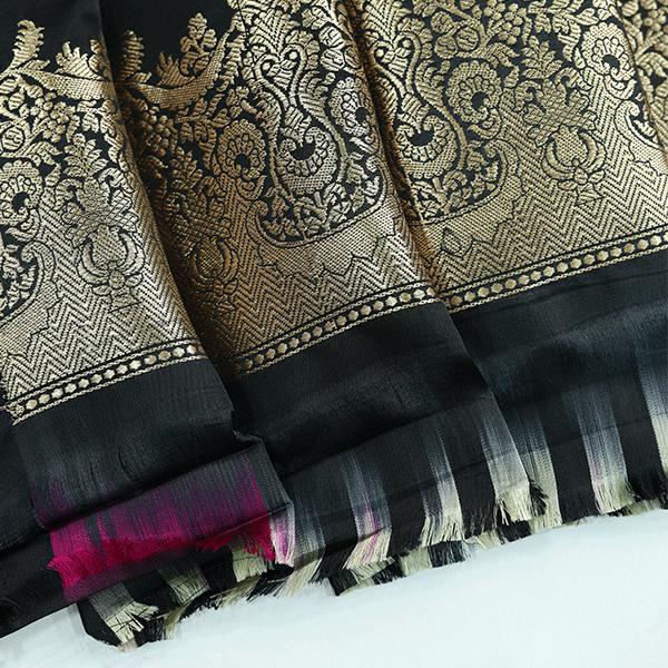Close-up of a premium black silk blouse fabric featuring intricate traditional gold zari weaving patterns and a soft, lustrous texture.