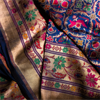 Close-up drape of a royal blue Paithani Patola silk saree showing the contrast between the geometric ikat patterns and the floral zari border.