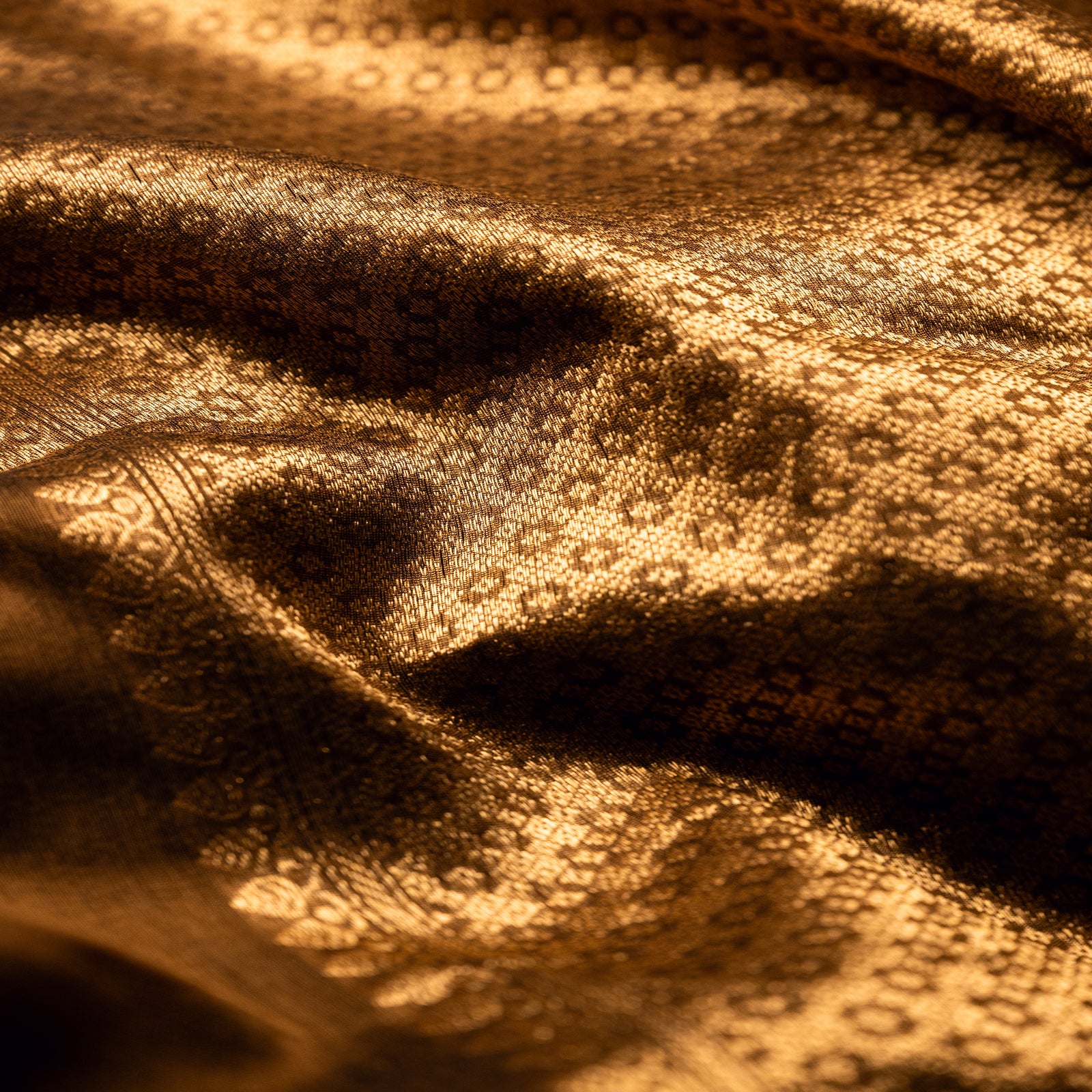 Close-up of the intricate gold zari weaving on a brown Alfi silk saree, highlighting the rich texture and artisanal craftsmanship