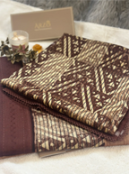 Folded brown cotton fabric with a geometric print, displayed with an Arzo-branded gift box and a small candle.