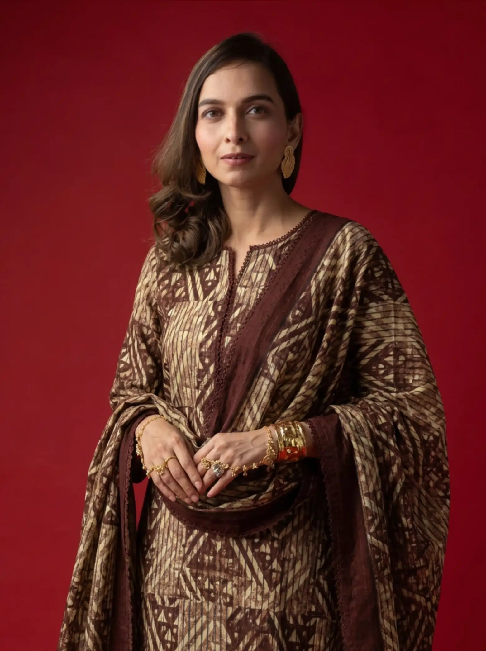 Woman wearing a brown and cream geometric-print traditional cotton kurta set with a matching dupatta against a solid red background