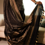 Close-up of the antique gold zari floral motifs and intricate border on a black handwoven Katan silk saree.