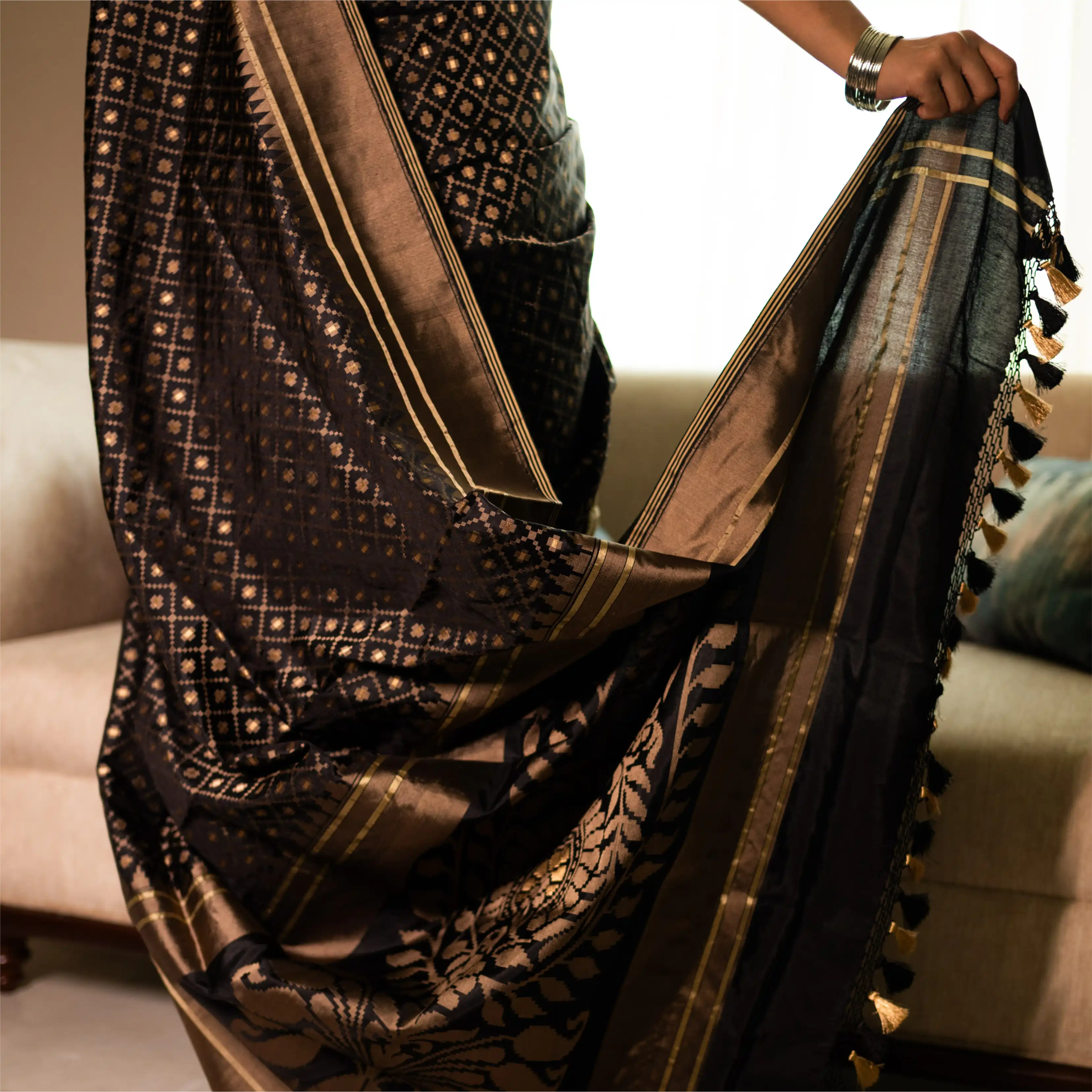 Close-up of the antique gold zari floral motifs and intricate border on a black handwoven Katan silk saree.