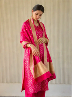 A woman modeling the striking red Cotton Alfi suit material, perfectly styled with a rich woven contrast border dupatta for festive elegance.
