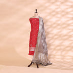 Crimson Radiance unstitched suit fabric in pure handwoven Katan silk with a vibrant red base and golden border, beautifully paired with a slate grey Resham and Zari work dupatta on a mannequin.