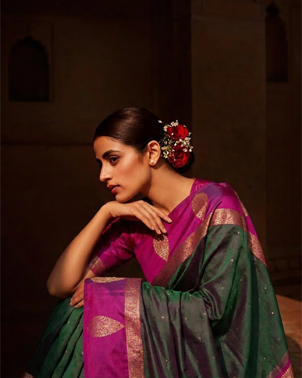 Close-up of a dark green and magenta Kanjivaram silk saree showcasing the detailed gold zari woven pallu and ornate floral motifs."