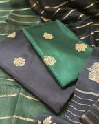 Close-up view of folded dark grey and green pure Banarasi silk fabrics, both featuring intricate gold zari weaving patterns.