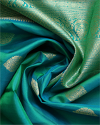 A neatly folded dark teal Kanjivaram silk saree, highlighting the richness of the zari work.