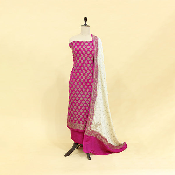 Deep maroon unstitched pure crepe silk suit featuring intricate golden booti embroidery, paired with a draped jasmine white patterned dupatta on a mannequin.