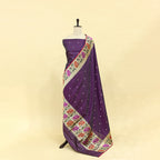 A mannequin displaying an elegant deep purple Banarasi silk suit, paired with a vibrant floral Kalamkari print dupatta featuring traditional intricate borders.
