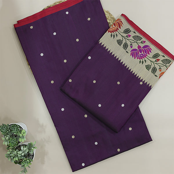 A beautiful flat-lay of a deep purple unstitched Banarasi silk suit fabric, featuring elegant gold zari bootis and a contrasting traditional floral border pattern