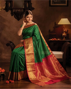 Woman wearing a premium emerald green pure silk Kanjivaram saree with an orange zari pallu.