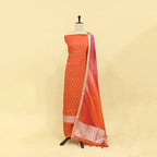 Fiery brick red tie and dye silk suit featuring a delicate white dotted pattern and a striking pink and gold accent border displayed on a mannequin.