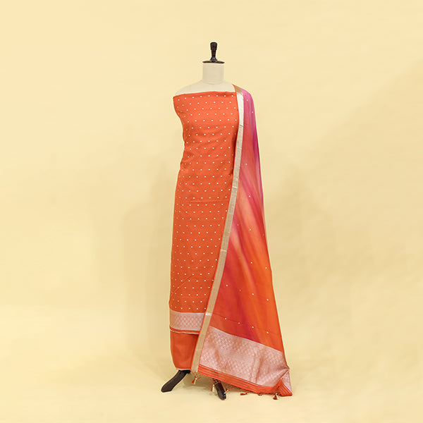 Fiery brick red tie and dye silk suit featuring a delicate white dotted pattern and a striking pink and gold accent border displayed on a mannequin.