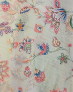 A detailed close-up of a light beige fabric featuring an intricate, multicolored floral and vine embroidery pattern, showcasing artisanal craftsmanship.