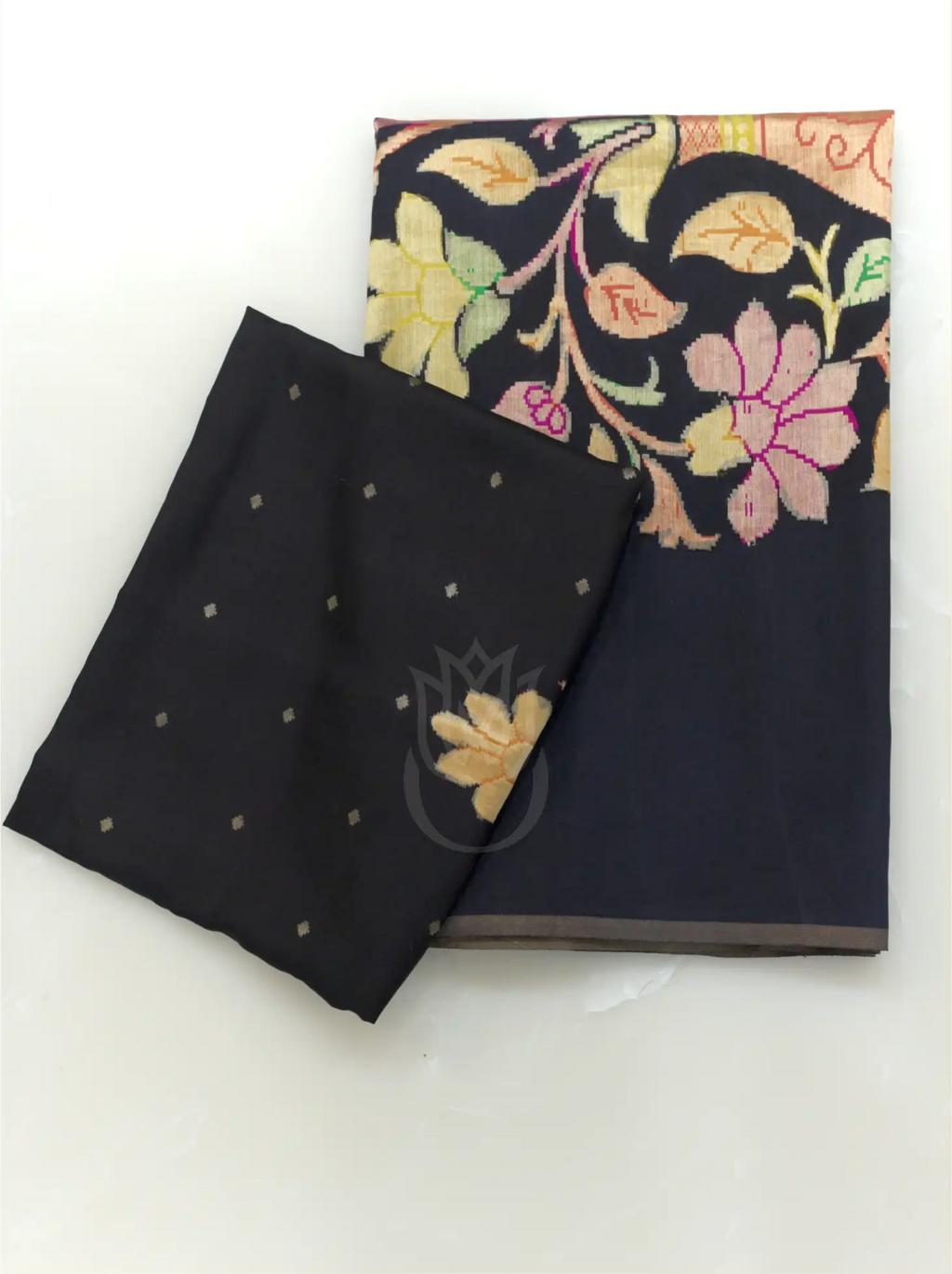 Folded handwoven pure georgette silk charcoal black suit fabric featuring gold micro bootis next to a matching dupatta with colorful woven floral motifs against a plain white background.