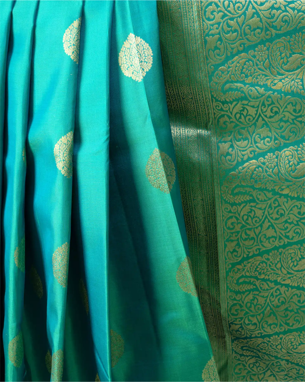 A full-length view showcasing the graceful drape and regal silhouette of the dark teal Kanjivaram saree.