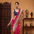 Woman posing in a premium fuchsia pink Tussar Georgette silk saree featuring an intricate multicolored weave border and elegant navy blue sleeveless blouse.
