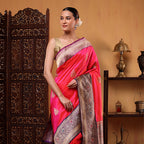 Woman wearing a vibrant fuchsia pink katan silk saree with handwoven gold sauna rupa boota work and a detailed traditional border, paired with a sleeveless golden blouse.