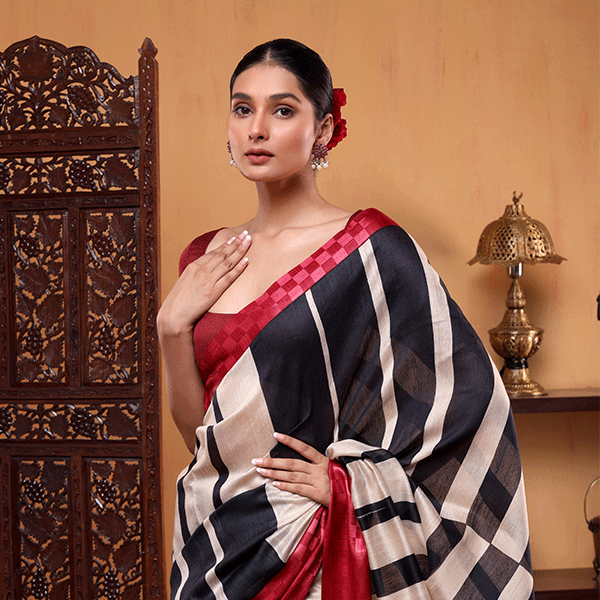 A woman wearing a light ivory handwoven Munga cotton silk saree with geometric black and off-white stripes, featuring a striking contrast fuschia border.