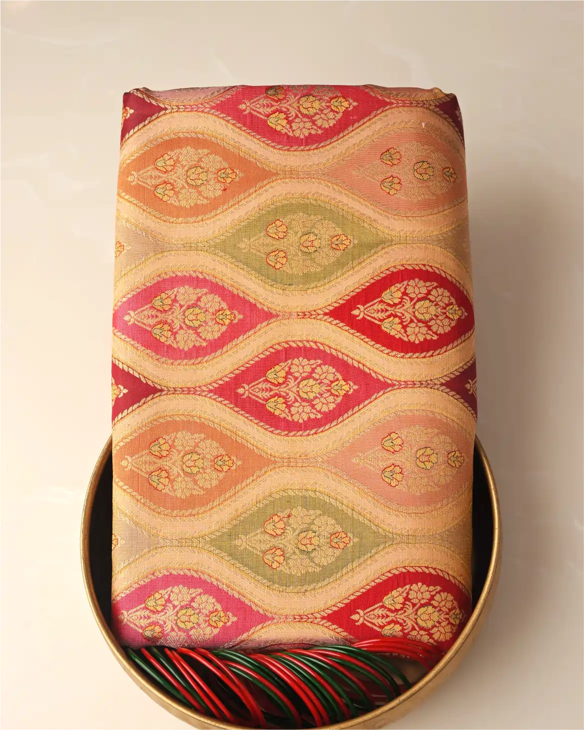 Close-up detail of a handwoven champagne gold and coral orange Rangkart Kanchipuram silk saree showing geometric zari patterns and woven floral motifs.