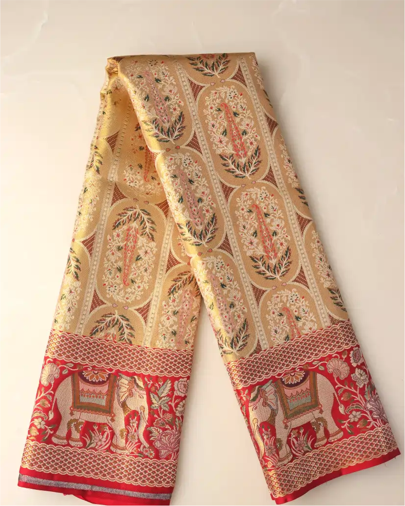 Folded length of a handwoven gold and red Kanchipuram silk saree showing intricate floral motifs and traditional woven elephant zari border.