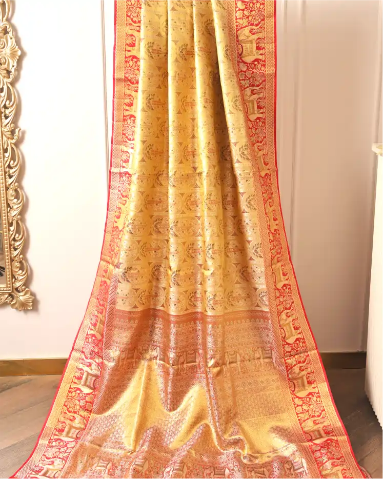 Full drape display of a handwoven gold and red Kanchipuram silk saree showing intricate body motifs and a traditional red elephant zari border.