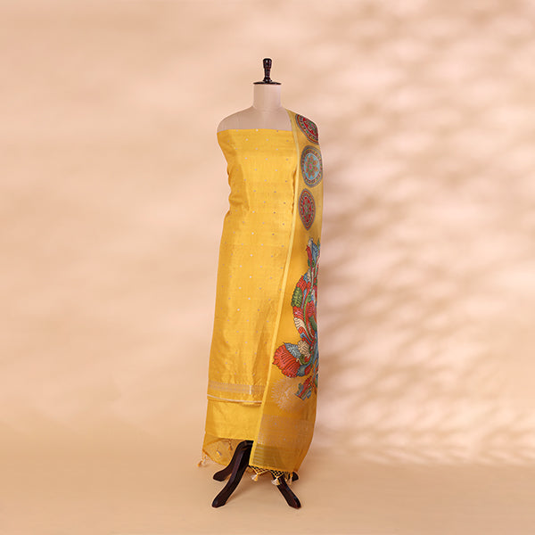 Unstitched golden yellow handwoven Banarasi silk suit set displayed on a mannequin, styled with a vibrant, multicolored traditional Kalamkari organza dupatta.
