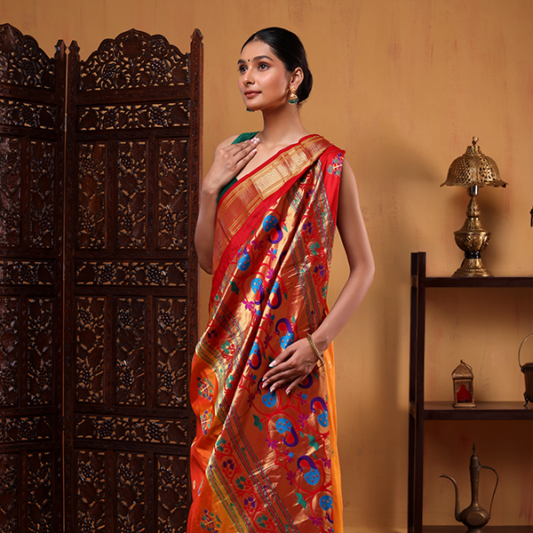 A side angle view of the Golden Sunset Paithani silk saree showcasing the vibrant red pallu intricately woven with traditional colorful peacock and floral motifs.