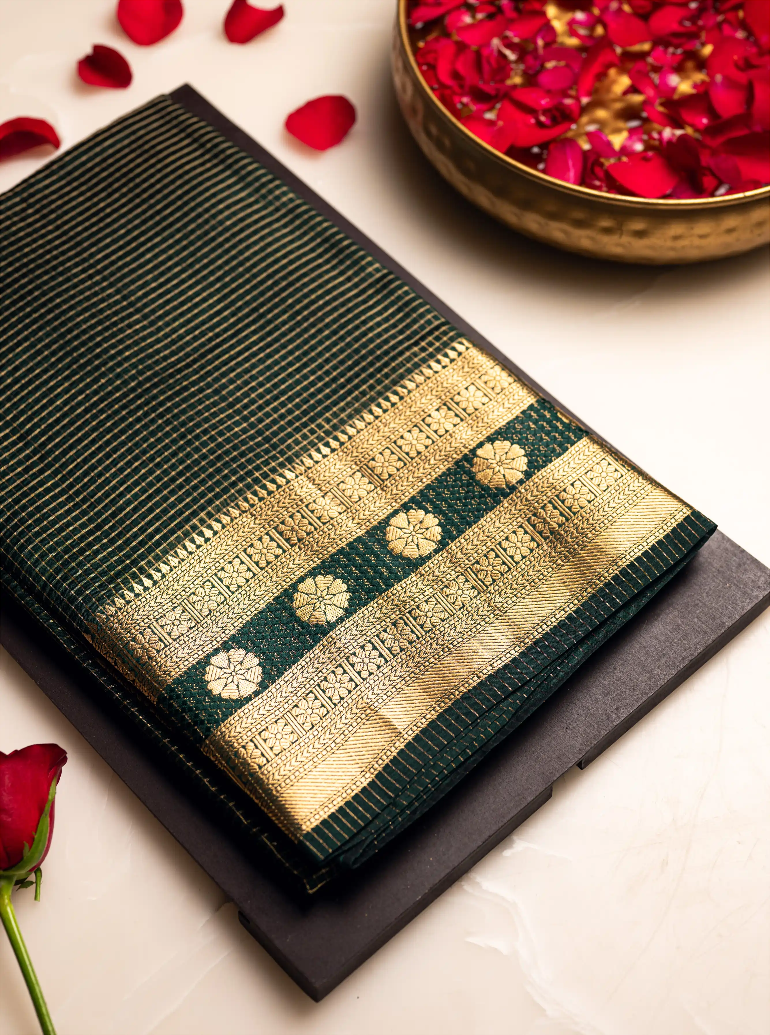 Green Handwoven Pure Katan Silk Saree with a gold zari border and grid pattern body, styled with red rose petals on a white background.