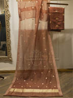 Sheer chocolate brown handwoven Banarasi Kora silk dupatta with starburst zari motifs displayed vertically alongside folded silk suit fabric on a wooden hanger, set near a gold ornate mirror