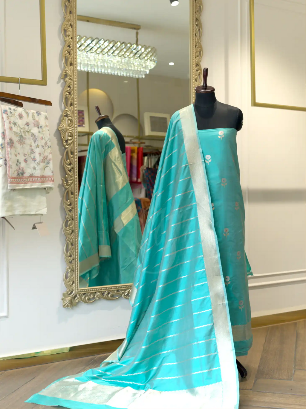 Unstitched Handwoven Banarasi Silk Suit Set in Sea Green draped on a black mannequin featuring floral booti work on shirt and striped gold zari dupatta in a boutique setting