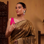 Model wearing a handcrafted earthy brown Alfi silk saree with gold zari floral motifs, paired with a vibrant pink sleeveless blouse.