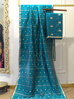 Handwoven teal blue Chinia silk dupatta with horizontal gold zari stripes draped on a gold stand next to a matching silk suit piece featuring gold floral booti work.
