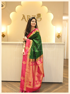 Woman posing in a handwoven dark green Mysore silk saree with a pink border and gold zari pattern from Arzo.