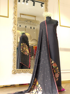 Handwoven pure georgette silk charcoal black suit fabric with gold micro bootis draped on a mannequin, featured alongside a matching dupatta with multi-color floral border motifs in a boutique setting.