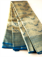 Handwoven metallic gold tissue Kanjivaram silk saree displayed in fan-folded pleats, featuring intricate dark teal zari brocade weave patterns and a crisp dark teal zari border.