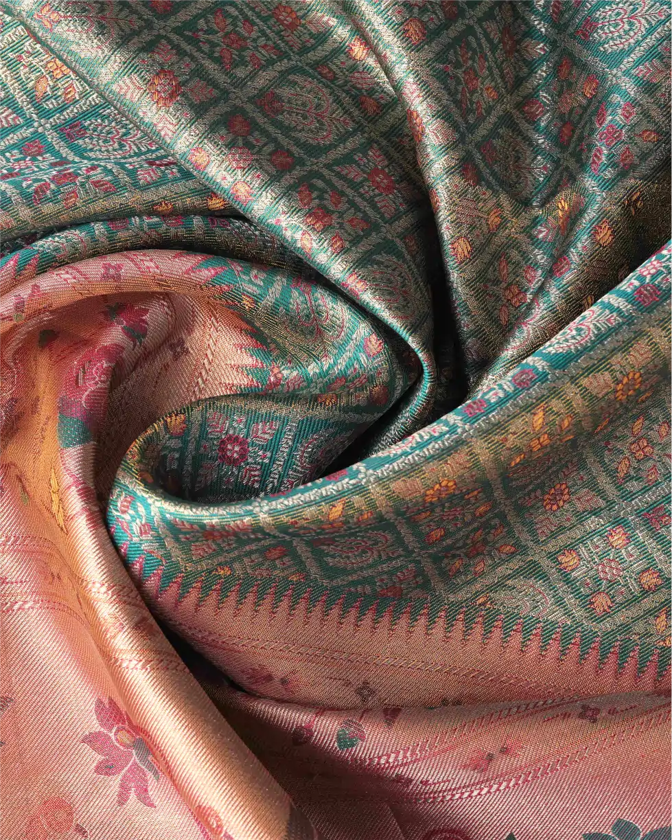 Close-up shot of draped green tissue Patola Kanjivaram silk saree showing shimmering weave texture, geometric lattice motifs, and pink zari pallu.