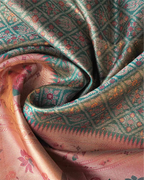 Close-up shot of draped green tissue Patola Kanjivaram silk saree showing shimmering weave texture, geometric lattice motifs, and pink zari pallu.