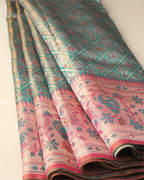Folded sea green tissue Patola Kanjivaram silk saree showing intricate geometric lattice motifs and a pink floral zari border.