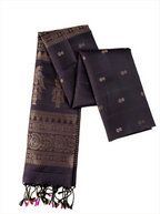 Deep royal aubergine Patola and Kanjivaram silk saree displayed lengthwise on a white background, highlighting large gold zari peacock motifs on the top layer, intricate geometric zari band weaving across the body, and black tassels with vibrant pink tied accents along the bottom fringe.