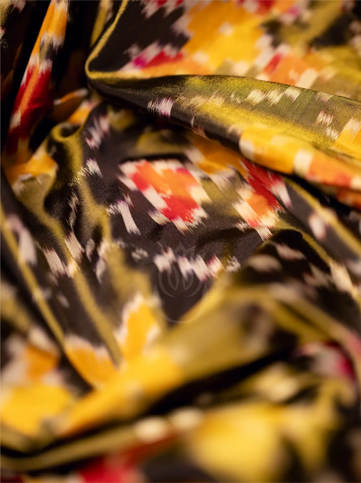 Close-up view of a folded handwoven Kanjivaram Patola silk saree highlighting the soft texture and geometric ikat geometric patterns in vibrant yellow, red, and black.